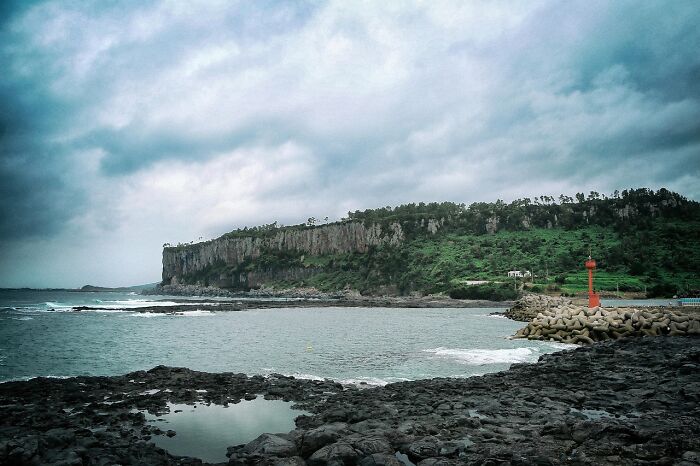 Coastal cliffs with lush greenery under a cloudy sky, showcasing one of nature's wonders.
