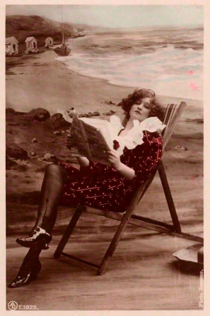 Woman in vintage attire reading on a beach chair, resonating with the past century's style and ambiance.
