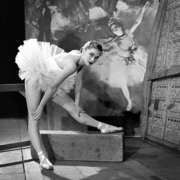 Ballerina in a 100-year-old photo, stretching on pointe, with vintage art backdrop showcasing resonance of history.