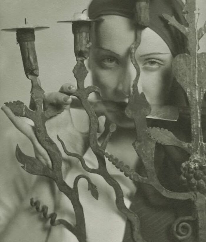 Vintage photograph of a person gazing through an ornate candelabra, showcasing timeless resonance.
