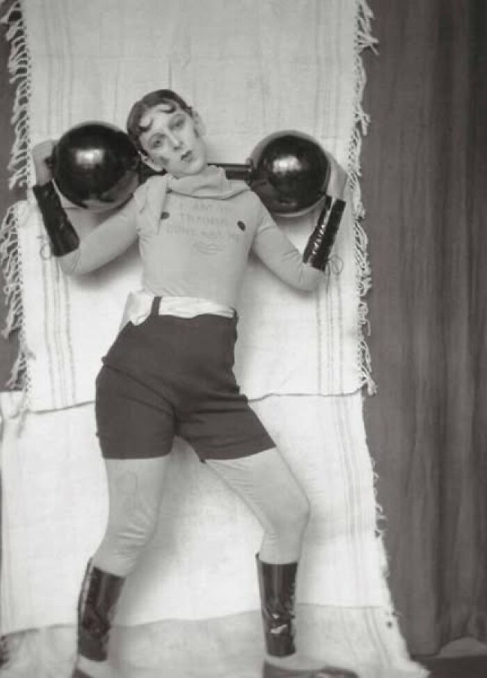 Vintage strongwoman lifting weights, showcasing a historical fitness pose.