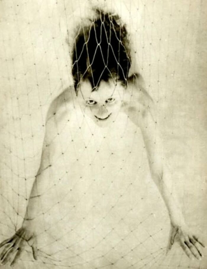 Vintage photo of a woman looking up through a net, showcasing enduring historical photography.