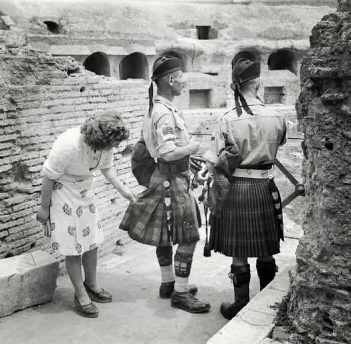 Two soldiers in kilts and a woman at a historical site, resonating with moments from a hundred years ago.