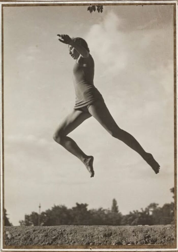 Person jumping mid-air over a ledge, showcasing timeless energy and dynamism from historical photography.