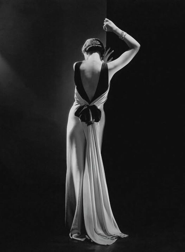 A woman in an elegant vintage gown, posing gracefully, showcasing historical fashion trends that resonate today.
