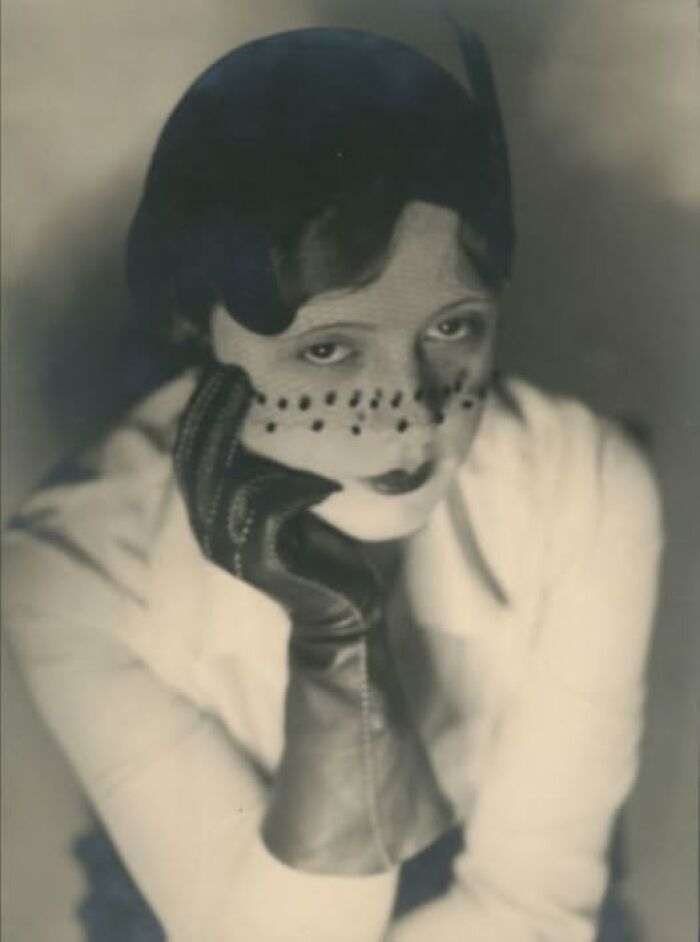 Vintage photo of a woman wearing a veil and gloves, embodying timeless beauty from more than a hundred years ago.