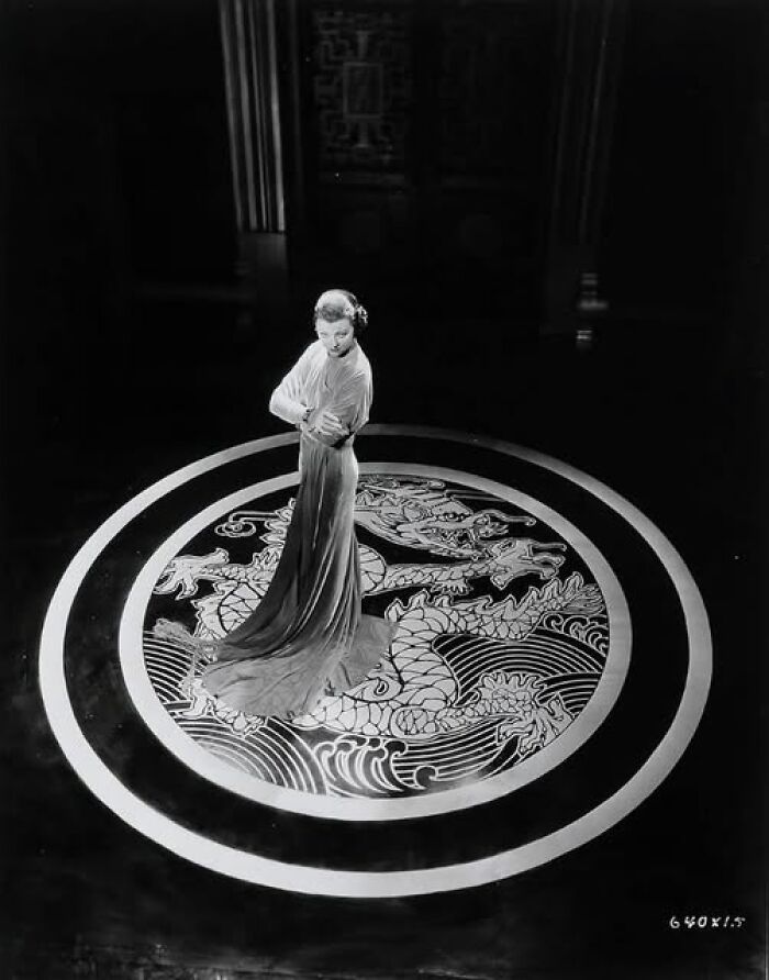 Vintage photo of a woman in an elegant dress standing on a decorated circular floor, showcasing timeless style.