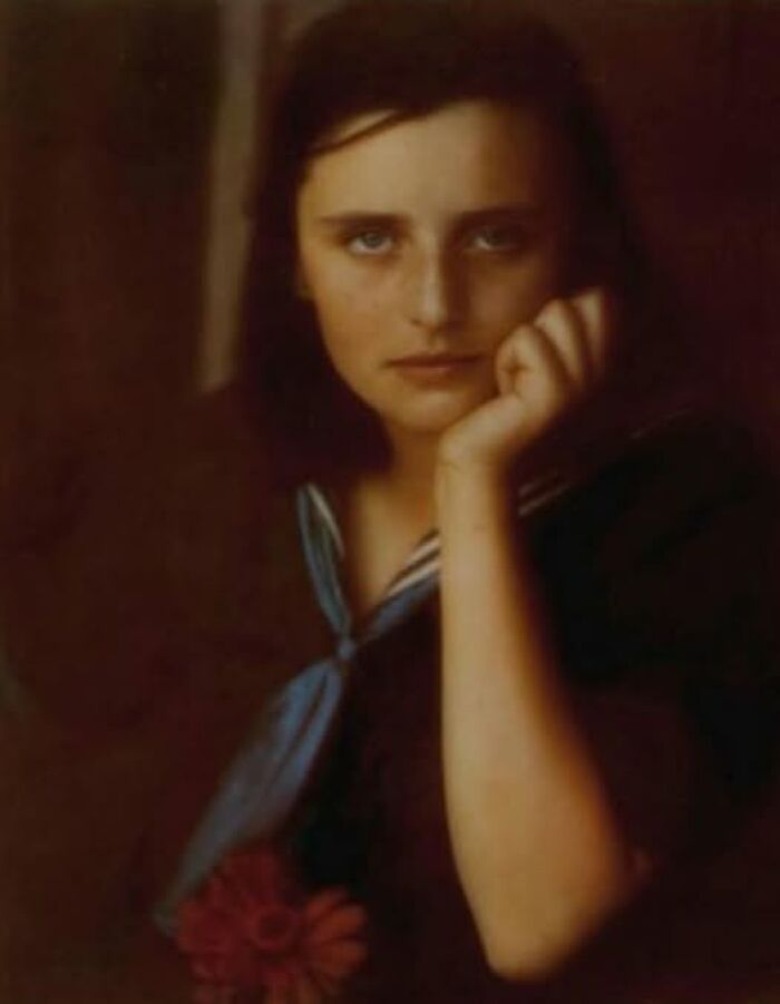 A woman from a hundred years ago, wearing a sailor-style outfit, gazes directly at the camera.