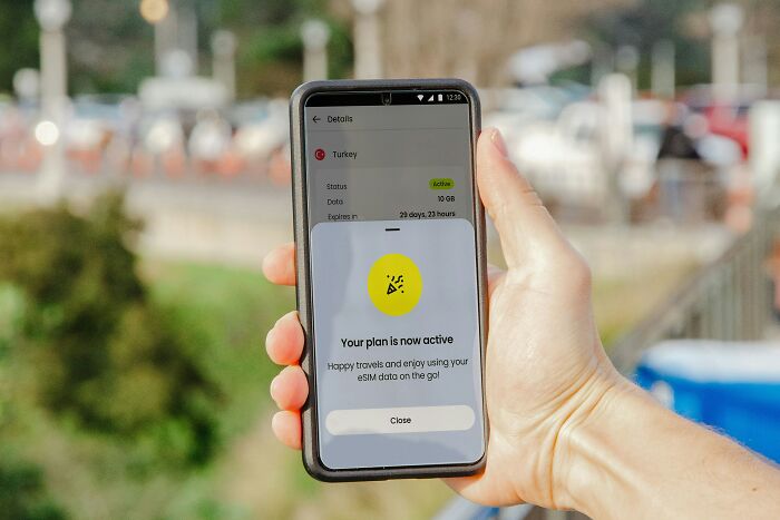 Person holding a smartphone displaying travel app notification about active eSIM plan.