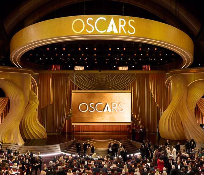 Oscars stage set for ceremony with audience seating, showcasing grand golden decor. Oscars stage set for ceremony with audience seating, showcasing grand golden decor.