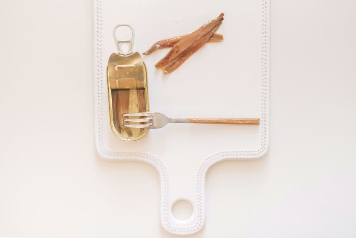 Canned anchovies on a white cutting board, representing ingredients often overlooked in cooking.