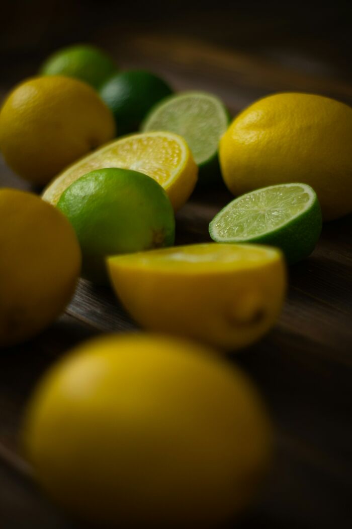 Fresh lemons and limes on a dark wooden surface, showcasing amazing ingredients.