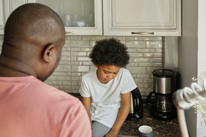 Parent and child having a discussion in the kitchen, highlighting differences in parenting approaches.
