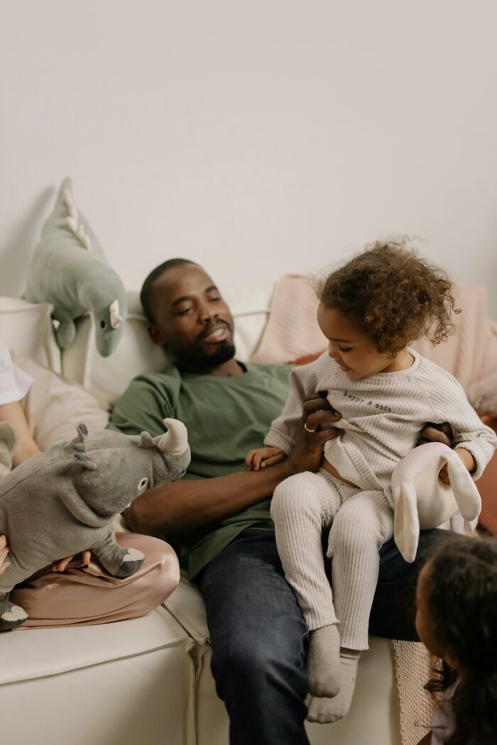 Parent relaxing on a couch with children and toys.