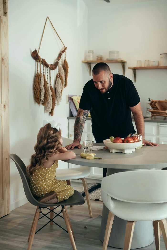 Parent talking to a child at a kitchen table, emphasizing modern parenting choices.