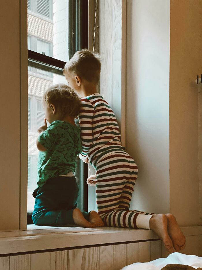 Children in pajamas looking out a window, illustrating the influence of parental decisions.