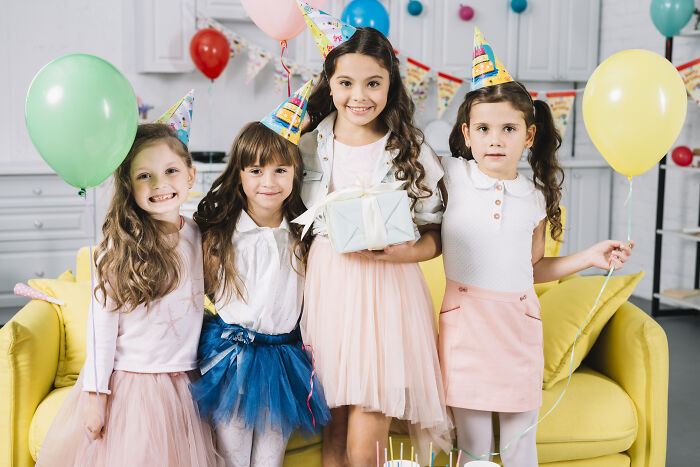Children at a birthday party in colorful outfits with balloons and gifts, highlighting joyful party moments.