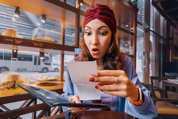 Woman shocked by dinner bill at a friend's fancy party, holding a receipt and menu. Woman shocked by dinner bill at a friend's fancy party, holding a receipt and menu.