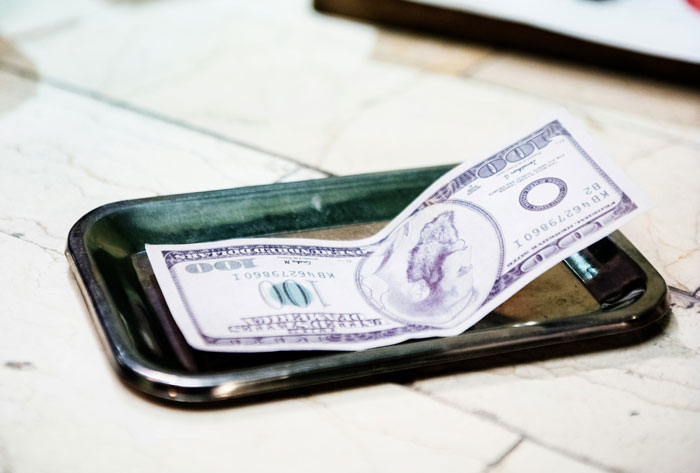$100 bill on a black serving tray, representing a financial nightmare at a friend's dinner party. $100 bill on a black serving tray, representing a financial nightmare at a friend's dinner party.