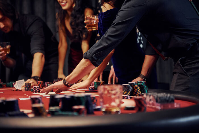 People engaged in an intense poker game during a legendary workplace moment with chips and drinks on the table.