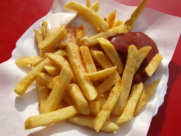 Crispy fast food fries with ketchup on a paper plate.