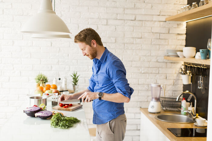 Man in a blue shirt preparing fresh vegetables, illustrating a reason to quit fast food.