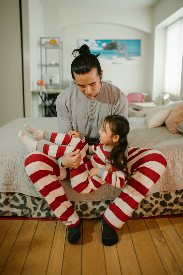 Parent and child in matching striped pajamas, enjoying a playful moment, showcasing a parenting hack at home.
