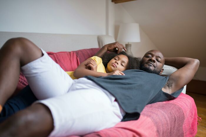 Father and daughter relaxing on a couch, illustrating parenting hacks at home.