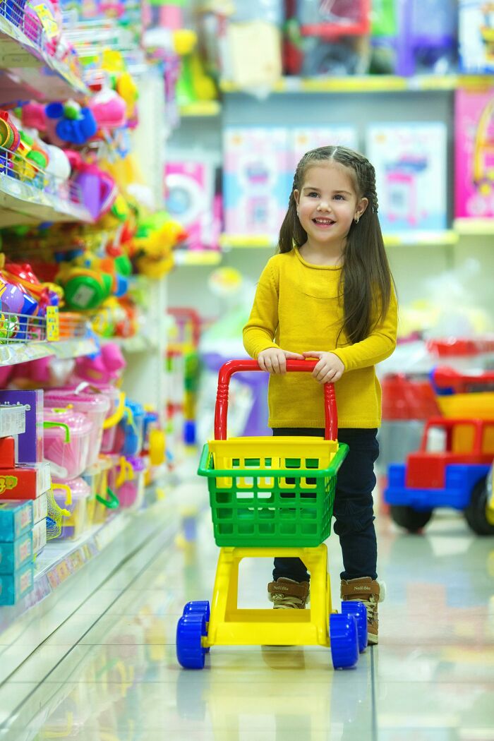 Child with toy shopping cart, demonstrating playful reverse psychology tricks at home.