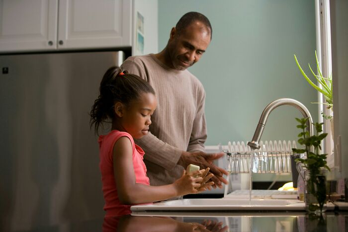 Father and daughter at kitchen sink, demonstrating parenting hacks in daily routines.