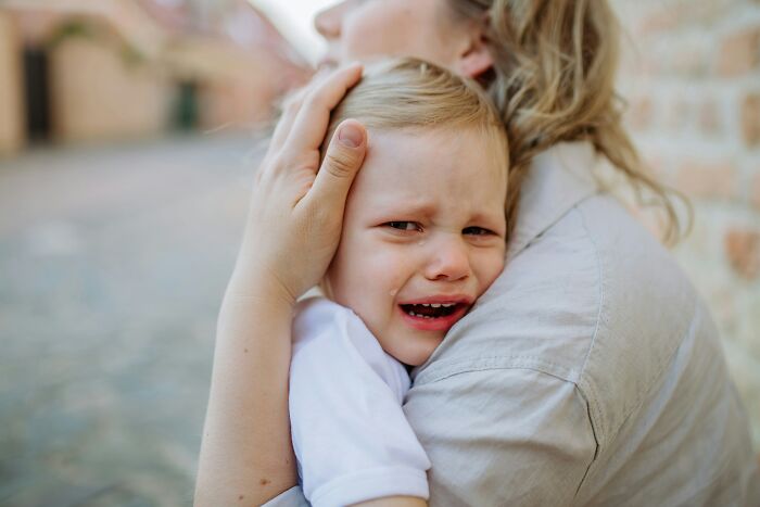 A parent comforting a crying child, demonstrating a reverse psychology trick at home.