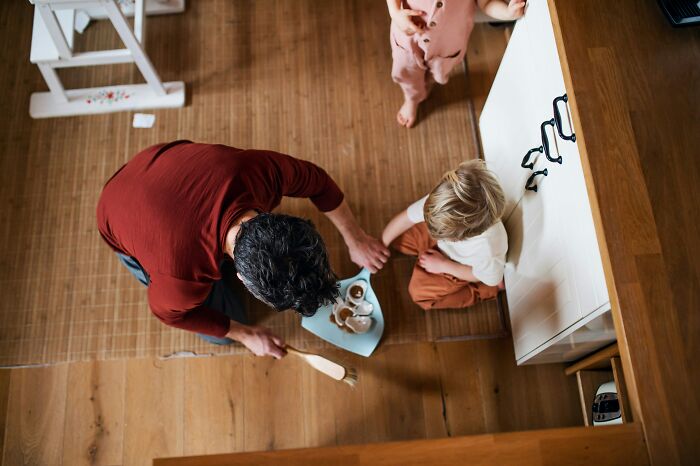 Adult helping child with a meal on a tray in a home setting, illustrating unexpected challenges of adulthood.