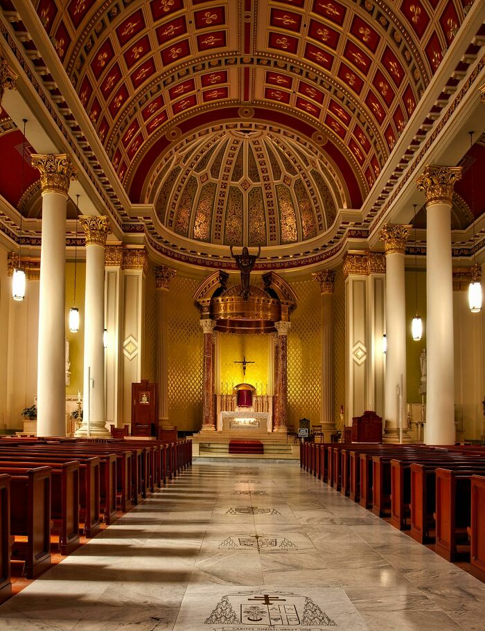 Ornate church interior with vibrant ceiling and altar, showcasing architectural beauty.