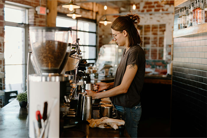 Barista preparing coffee in a cafe setting, highlighting the pay it forward culture in customer service.