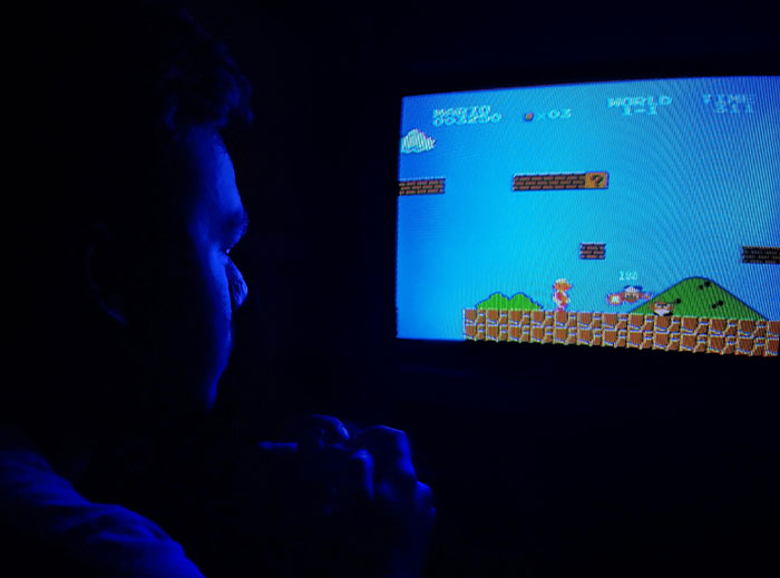 Person holding a game controller playing a classic retro video game on a screen, symbolizing petty grudges.