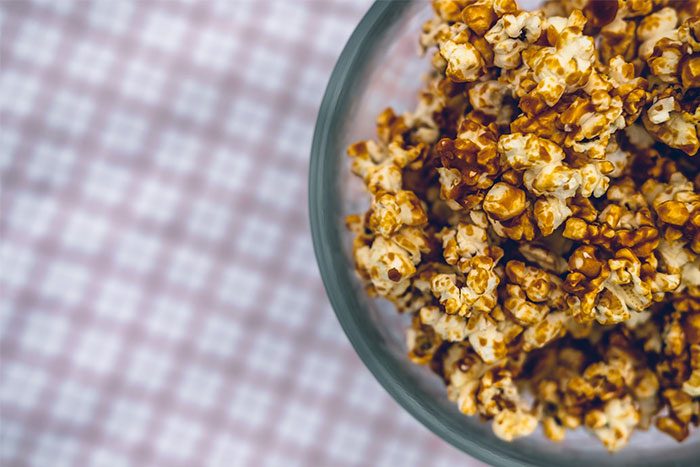Caramel popcorn in a glass bowl on a checkered tablecloth, related to petty grudges.