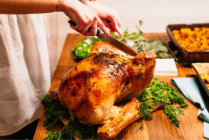 Person carving a roasted turkey at a festive dinner, illustrating a petty grudge related to holiday meals.