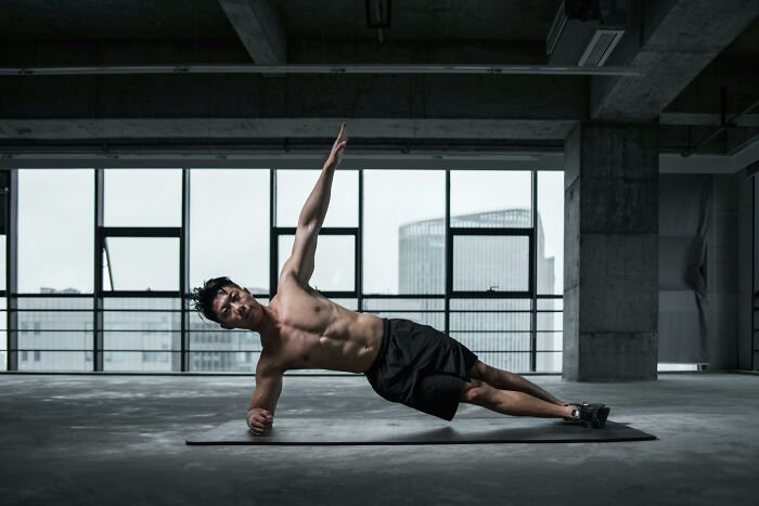 Man performing a side plank exercise indoors, highlighting fitness myths.