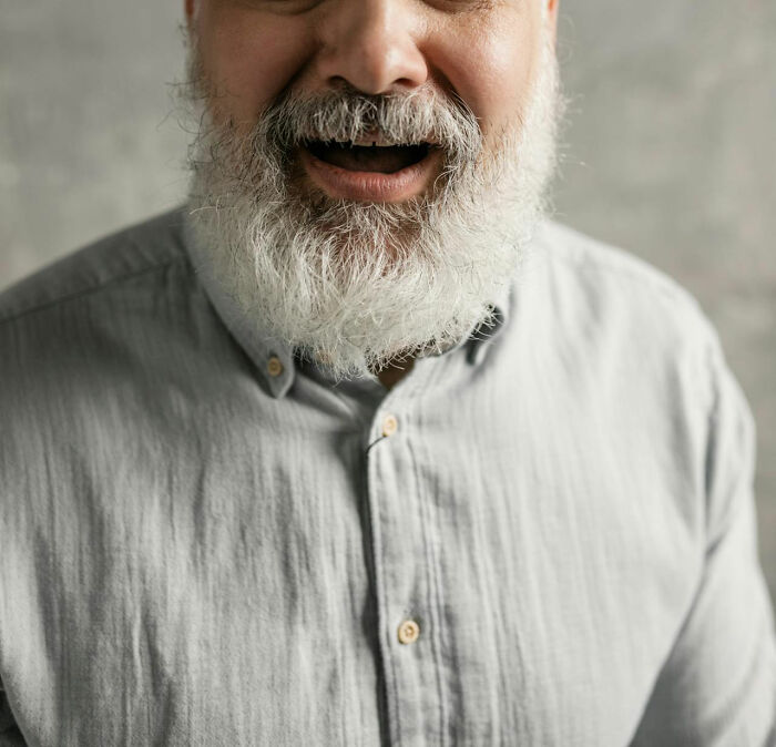 Bearded man in a light shirt smiling, capturing a moment related to a family member's creepy statement.