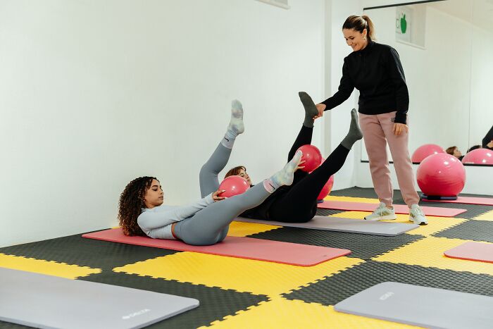 Women exercising with stability balls on mats, guided by a trainer, illustrating common fitness myths.