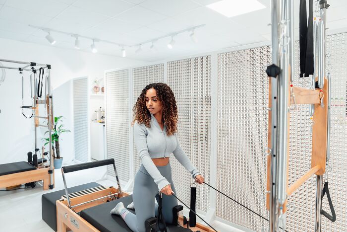 Woman exercising on Pilates reformer, focusing on busting fitness myths.