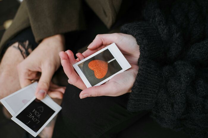 Hands holding a photo of a heart-shaped lollipop, ideal for simple Valentine's gift ideas.