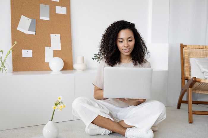 Person using a laptop in a bright room, illustrating assumptions about jobs with minimalistic decor.