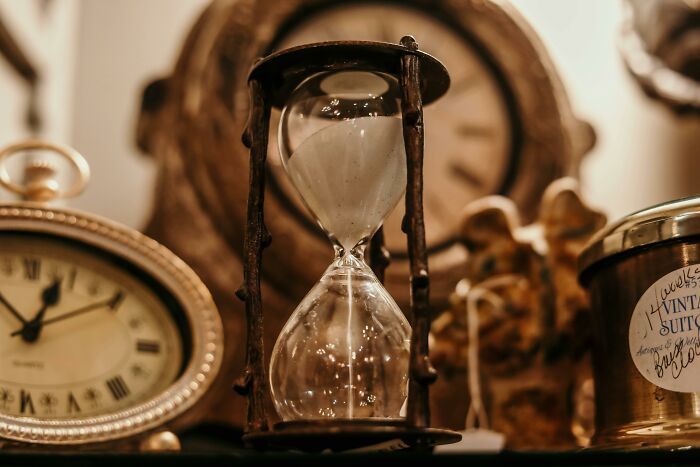 Hourglass and vintage clocks symbolizing harsh life lessons and the passage of time.
