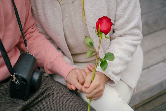 Two people holding hands, one holding a rose, symbolizing adorable Valentine’s gift ideas.