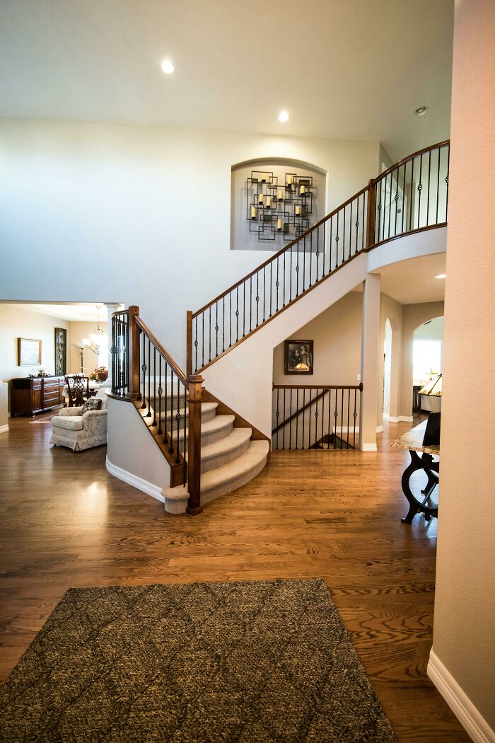 Elegant staircase in a well-lit home interior, featuring hardwood floors and decorative wall accents.