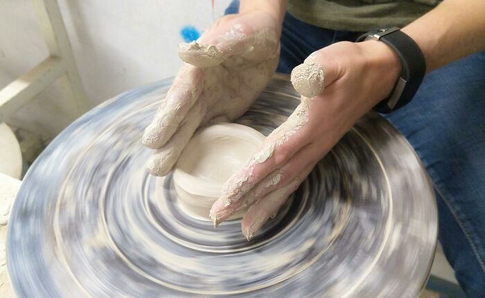 Hands shaping clay on a pottery wheel, creating art inspired by hilarious conversations.