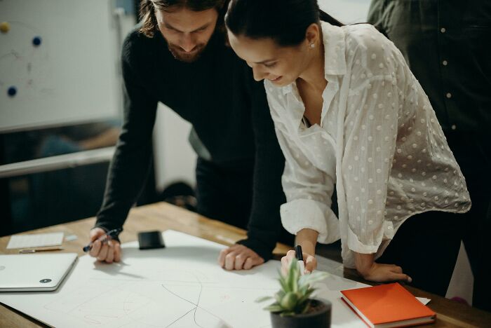 Two people collaborating at a desk, discussing a project, highlighting work skills people lack.