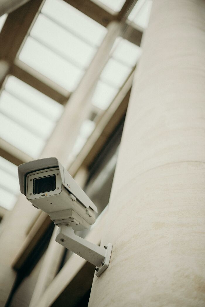 Security camera mounted on a pillar in an office building capturing insane workplace moments and legendary status events.