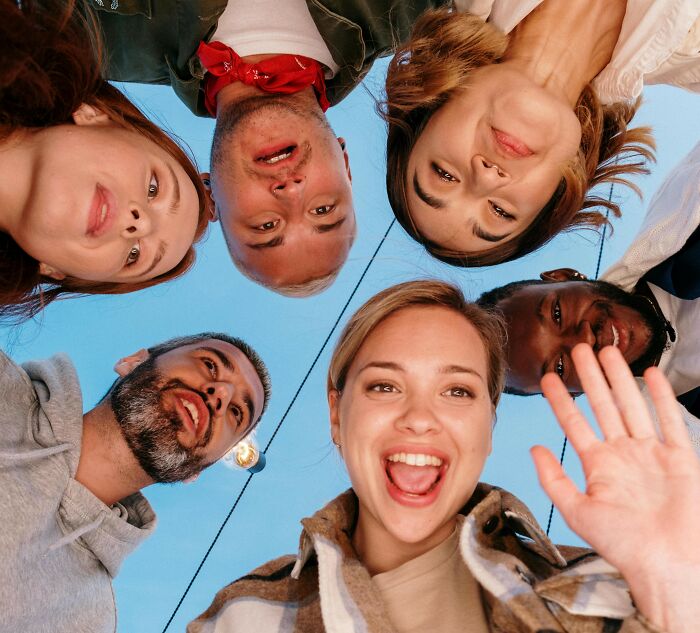 A group of smiling friends looking down at the camera, representing love and connection.